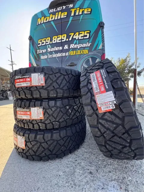 New Nitto Ridge Grappler tires stacked in front of Rudy's Mobile Tire van